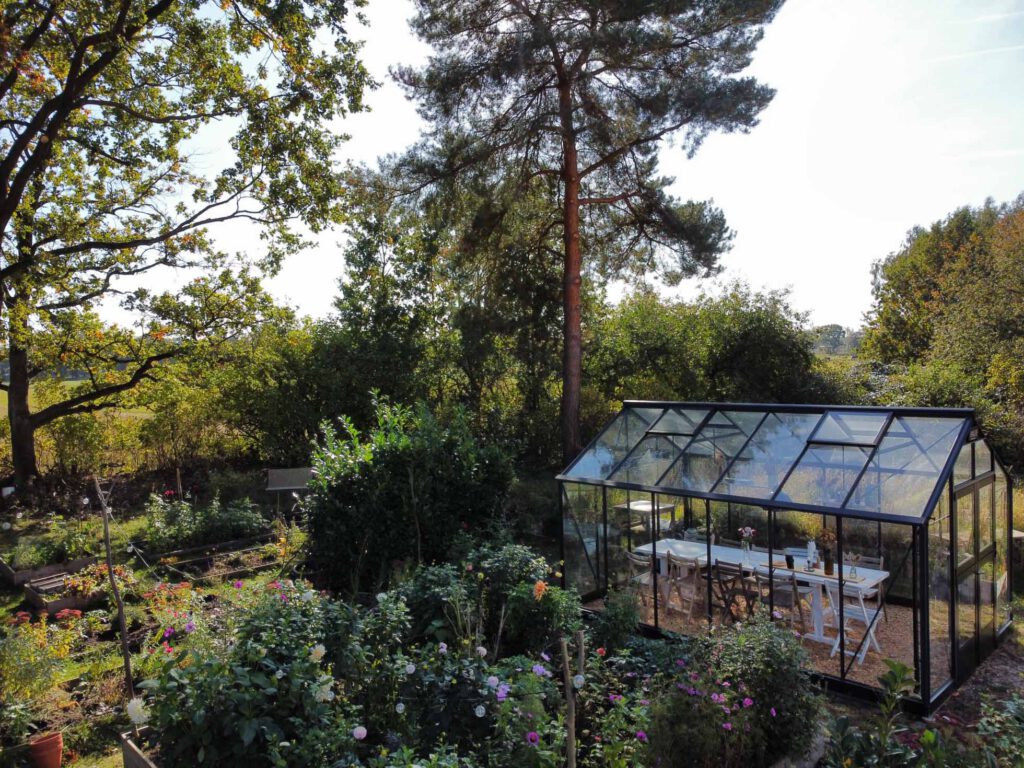 Orangerie der Bahnhofszeit umgeben von Wald und Garten.